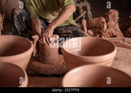 mano di uomini che lavorano sulla ruota del vasaio. Mani sculpta un mortaio da creta pot. Creta ware fatto a mano sulla ruota del vasaio in thailandia. Foto Stock