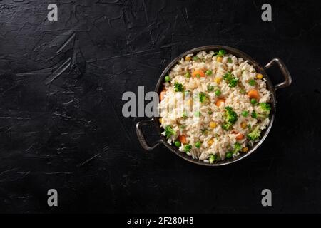 Riso vegano, mescolare fritto, sparato dall'alto su uno sfondo nero Foto Stock