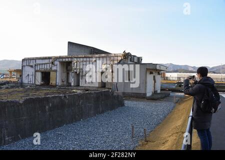 Ishinomaki, Giappone. 9 marzo 2021. Un visitatore scatta foto delle rovine della scuola elementare di Okawa a Ishinomaki, Giappone, il 9 marzo 2021. Una scuola elementare pubblica nella prefettura di Miyagi ha perso più di 80 vite nello tsunami a seguito del terremoto del 2011 marzo nel Giappone nordorientale. Dieci anni dopo, le rovine dell'edificio scolastico raccontano ancora l'inimmaginabile tragedia della calamità. PER ANDARE CON 'Feature: 10 anni dopo, la scuola giapponese di tsunami-colpito ancora dice tragedia inimmaginabile' Credit: Gang Ye/Xinhua/Alamy Live News Foto Stock