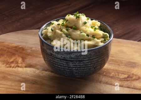 Purea di Pomme, una foto di una ciotola di purè di patate con erbe su uno sfondo rustico Foto Stock