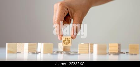 Uomo di affari mano vicino selezionare l'obiettivo e l'icona di obiettivo sul successo di affari di concetto di legno del blocco. Foto Stock