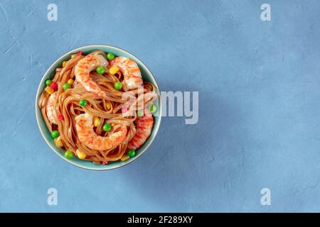 Noodle, mescolare fritti con gamberi e verdure, top shot su uno sfondo blu Foto Stock