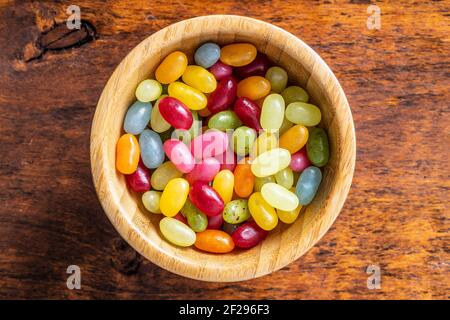 Fagioli di gelatina colorati e dolci in ciotola di legno su tavolo di legno. Vista dall'alto. Foto Stock