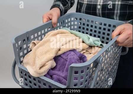 Un uomo che tiene un cestino pieno di asciugamani. Foto Stock