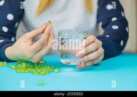 Omega 3 capsule di olio di pesce che fuoriescono da una bottiglia su sfondo blu. Fuoco selettivo. Foto Stock