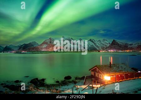 Aurora boreale o Aurora borealis su atipici case rosse rorbu, Svolvaer Lofoten Norvegia Foto Stock