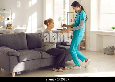 Infermiera amichevole all'ospedale o alla struttura vivente assistita che dà il vetro di acqua a donna matura Foto Stock