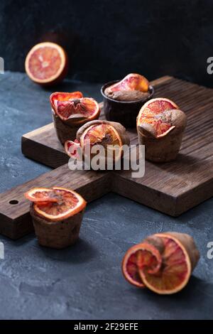 Arance di sangue, muffin al cioccolato con brownie su un pannello di quercia scuro sfondo intonaco scuro verticale Foto Stock