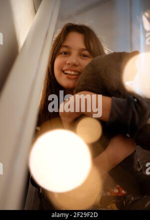 Ragazze in pigiama grigio abbracciano un gatto blu seduto sopra a sulle scale Foto Stock