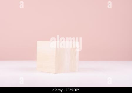 Podio in legno naturale a forma di cubo su tavola bianca e parete rosa per l'esposizione dei prodotti. Foto Stock