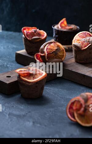 Muffin color arancio cioccolato sangue su fondo di intonaco scuro verticale Foto Stock