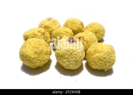 Dolce indiano a forma di sfera di colore giallo fatto di rava, zucchero, uvetta e anacardi. Foto Stock