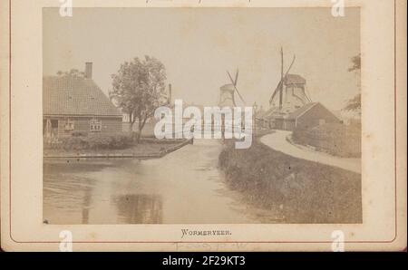 Gezicht op een sloot met molens, bebouwing en mensen in Wormerveer; Wormerveer..Part di LeporelloLBum con 28 foto di Amsterdam e dintorni. Per vedere il pelmolen il giovane sgabello (a destra) e il frantoio il cavallo bianco (centro). Dietro di questo i pulcini del frantoio De Moriaan sopra un capannone. Foto Stock