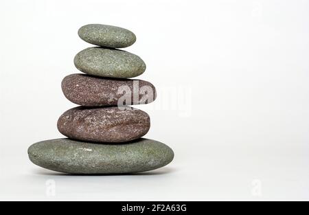 Pietre equilibrate l'una sull'altra contro uno sfondo bianco Foto Stock