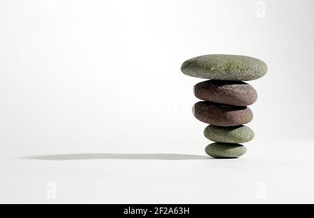Pietre equilibrate l'una sull'altra contro uno sfondo bianco Foto Stock