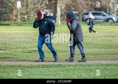 WIMBLEDON LONDRA, REGNO UNITO 11 MARZO 2021. La gente lotta nei conditons blusty mentre camminano sul comune di Wimbledon. L'ufficio MET ha emesso avvisi meteo per tutta l'Inghilterra e il Galles su venti di forza di scisto che possono raggiungere 80 mph, il che potrebbe compromettere le linee elettriche e l'interruzione del viaggio. Credit amer Ghazzal/Alamy Live News Foto Stock