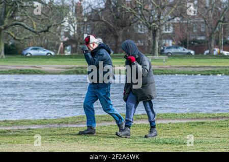 WIMBLEDON LONDRA, REGNO UNITO 11 MARZO 2021. La gente lotta nei conditons blusty mentre camminano sul comune di Wimbledon. L'ufficio MET ha emesso avvisi meteo per tutta l'Inghilterra e il Galles su venti di forza di scisto che possono raggiungere 80 mph, il che potrebbe compromettere le linee elettriche e l'interruzione del viaggio. Credit amer Ghazzal/Alamy Live News Foto Stock