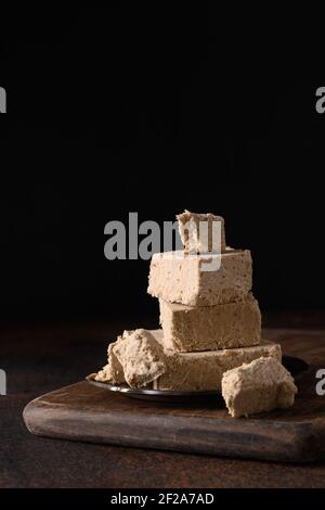 Gustosa halva dolce orientale preparato da semi di girasole su sfondo scuro. Verticale orientale. Primo piano. Foto Stock