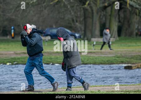 WIMBLEDON LONDRA, REGNO UNITO 11 MARZO 2021. La gente lotta nei conditons blusty mentre camminano sul comune di Wimbledon. L'ufficio MET ha emesso avvisi meteo per tutta l'Inghilterra e il Galles su venti di forza di scisto che possono raggiungere 80 mph, il che potrebbe compromettere le linee elettriche e l'interruzione del viaggio. Credit amer Ghazzal/Alamy Live News Foto Stock