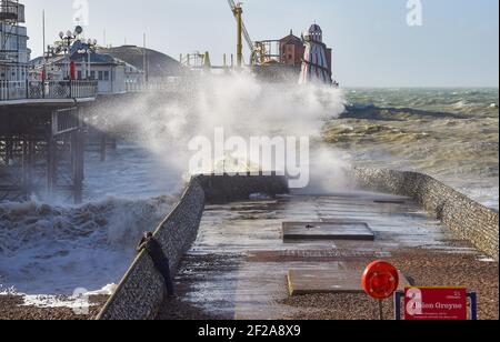 Brighton UK 11 marzo 2021 - UN fotografo cattura le onde che si infrangono sul lungomare di Brighton vicino al molo mentre il tempo tempestoso batte oggi la costa meridionale : Credit Simon Dack / Alamy Live News Foto Stock