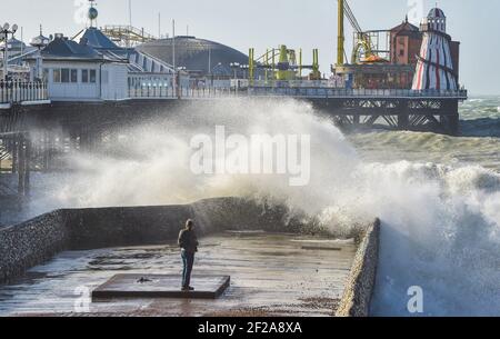 Brighton UK 11 marzo 2021 - UN fotografo cattura le onde che si infrangono sul lungomare di Brighton vicino al molo mentre il tempo tempestoso batte oggi la costa meridionale : Credit Simon Dack / Alamy Live News Foto Stock