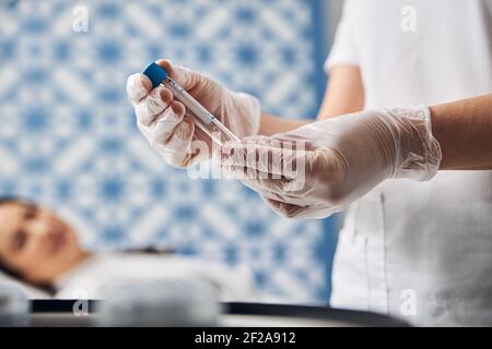 Mani di un medico che tengono una provetta in vetro Foto Stock