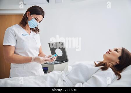 Medico femminile in maschera medica preparazione siringa per iniezione Foto Stock