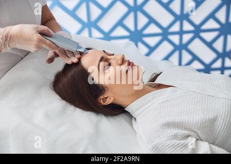 Donna attraente che riceve il trattamento facciale in clinica di cosmetologia Foto Stock