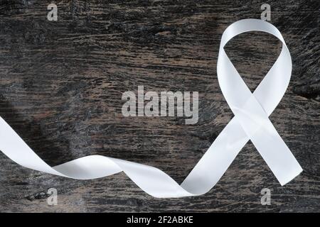 Vista dall'alto del nastro bianco su sfondo di legno scuro. Concetto di consapevolezza del cancro polmonare. Foto Stock