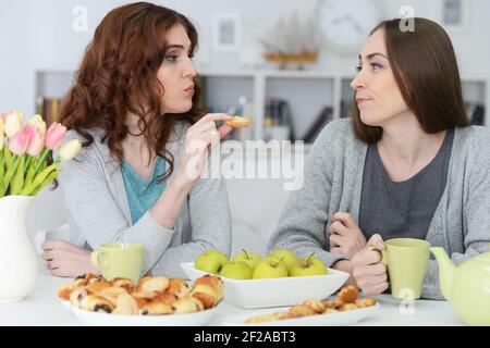 Due femmina sorridente amici seduti a tavola Foto Stock