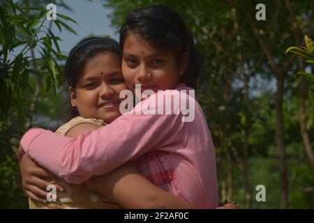 Primo piano di due belle ragazze indiane bengalesi adolescenti che si abbracciano a vicenda, focalizzazione selettiva Foto Stock