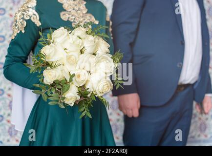 Nikah è una cerimonia di nozze musulmana. Lo sposo e lo sposo sono affiancati. La ragazza sta tenendo un bouquet di rose del tè nelle sue mani. Foto Stock