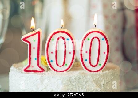 Candela di compleanno come numero cento in cima alla torta dolce sul tavolo, 100th compleanno Foto Stock