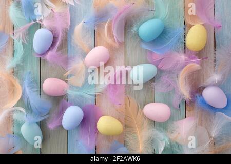 Buon concetto di pasqua. Colorate uova di Pasqua e piume su sfondo di legno. Disposizione piatta. Foto Stock