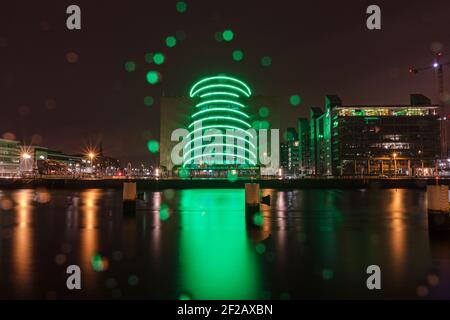 Centro Congressi di Dublino nella notte delle piogge il giorno di St Patricks con alcune luci delle fate, riflessione della luce nelle piogge, illuminazione verde, retroilluminazione verde Foto Stock
