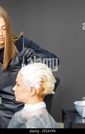 Donna parrucchieri tintura capelli di giovane donna caucasica in capelli salone Foto Stock