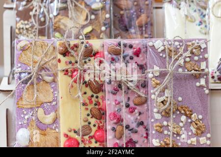 Un set di vari cioccolatini bianco, rosa, marrone, amaro, latte avvolto in una confezione trasparente con un arco di corda di iuta. Foto Stock