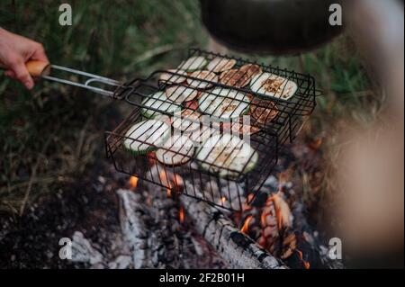 Accoppia in un plaid a scacchi arrostendo marshmallows sul fuoco vicino alla casa del rimorchio. Foto Stock