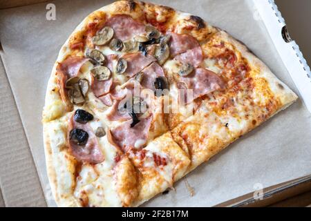 La pizza di famiglia, a metà ovale, è composta da due tipi, margarita, funghi prosciutto. Concetto di consegna di cibo, da asporto, cucina, fast food, togetherness. In alto Foto Stock