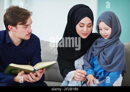 Giovane famiglia musulmana che legge il Corano durante il Ramadan Foto Stock