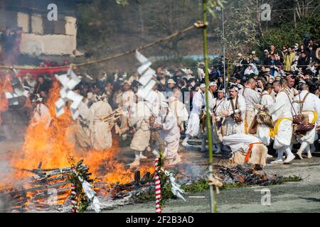 Shugenja buddista aggiungendo bastoni di preghiera di legno al falò al Matsuri di Hiwatari - Fire Walking Festival, Monte Takao, Hachioji, Giappone Foto Stock