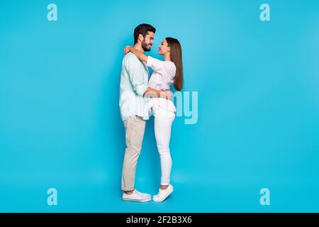 Foto di profilo di dimensioni complete di due belle persone abbraccio guardare l'uno l'altro occhi isolati su sfondo di colore blu Foto Stock