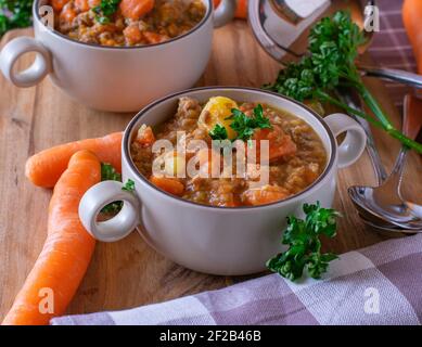 Stufato di lenticchie con carne tritata, patate e carote servite in ciotole rustiche per zuppe Foto Stock