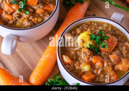 Stufato di carote con carne tritata, lenticchie e patate serviti in coppe di zuppa dall'alto Foto Stock