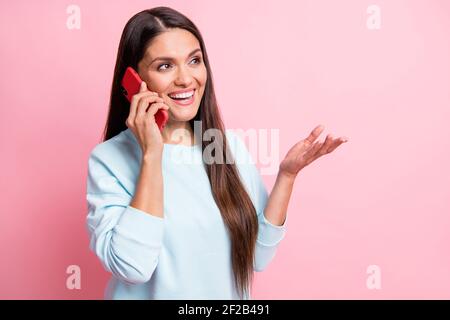 Ritratto fotografico della brunetta che parla sul telefono cellulare gesturando le mani guardando lo spazio vuoto isolato su sfondo di colore rosa pastello Foto Stock