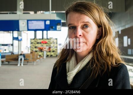 Breda, Paesi Bassi. La metà degli adulti donna caucasica presso la Stazione Ferroviaria di la piattaforma 3, aspettando il suo treno di collegamento in direzione est. Foto Stock