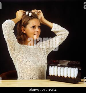 Negli anni '60. Una giovane donna usa bobine riscaldate elettricamente e avvolge i capelli intorno a loro, ottenendo un capelli ricci. Svezia 1968 Foto Stock