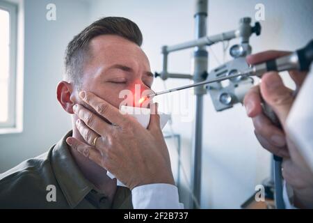 Paziente presso la clinica ENT. Specialista medico - Otolaringologo facendo esame del naso del giovane uomo. Foto Stock
