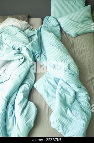 Letto non fatto con piumoni e cuscini a righe rigati. Concetto di comfort, stile di vita, relax Foto Stock