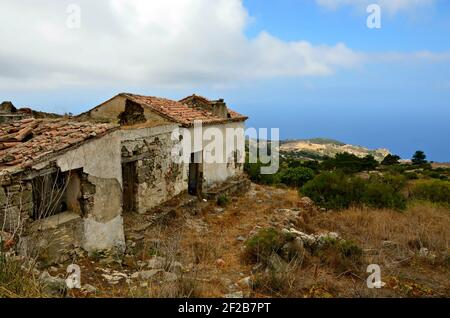 Paesaggio con rovine di una vecchia casa rurale tradizionale che si affaccia sul Mar Egeo meridionale, nell'isola di Karpathos, Grecia Ddecanese. Foto Stock